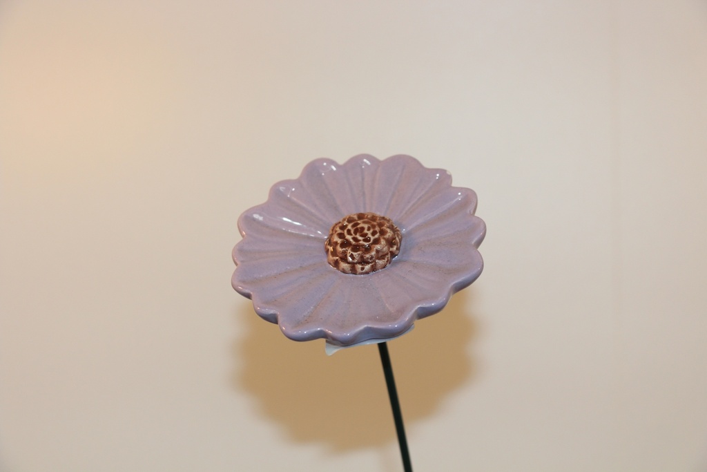 Flor decorativa em cerâmica lilás com centro em espiral e haste metálica